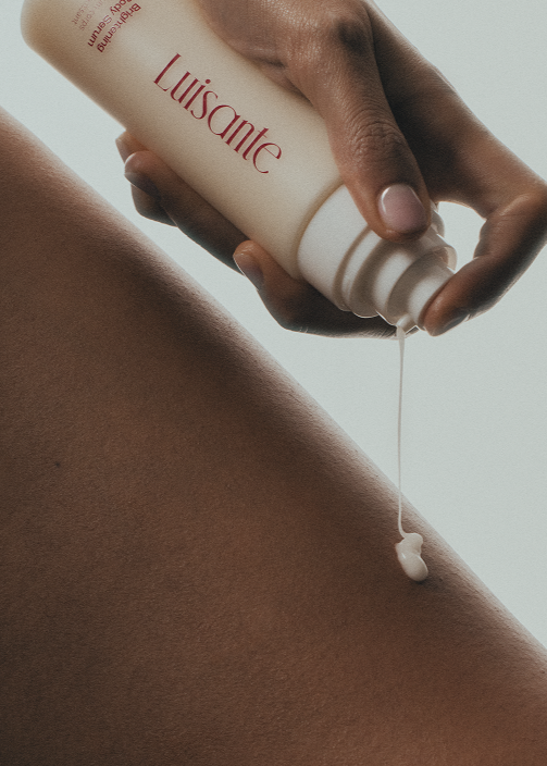Hand holding a bottle labeled 'Luisante' dripping serum onto skin

