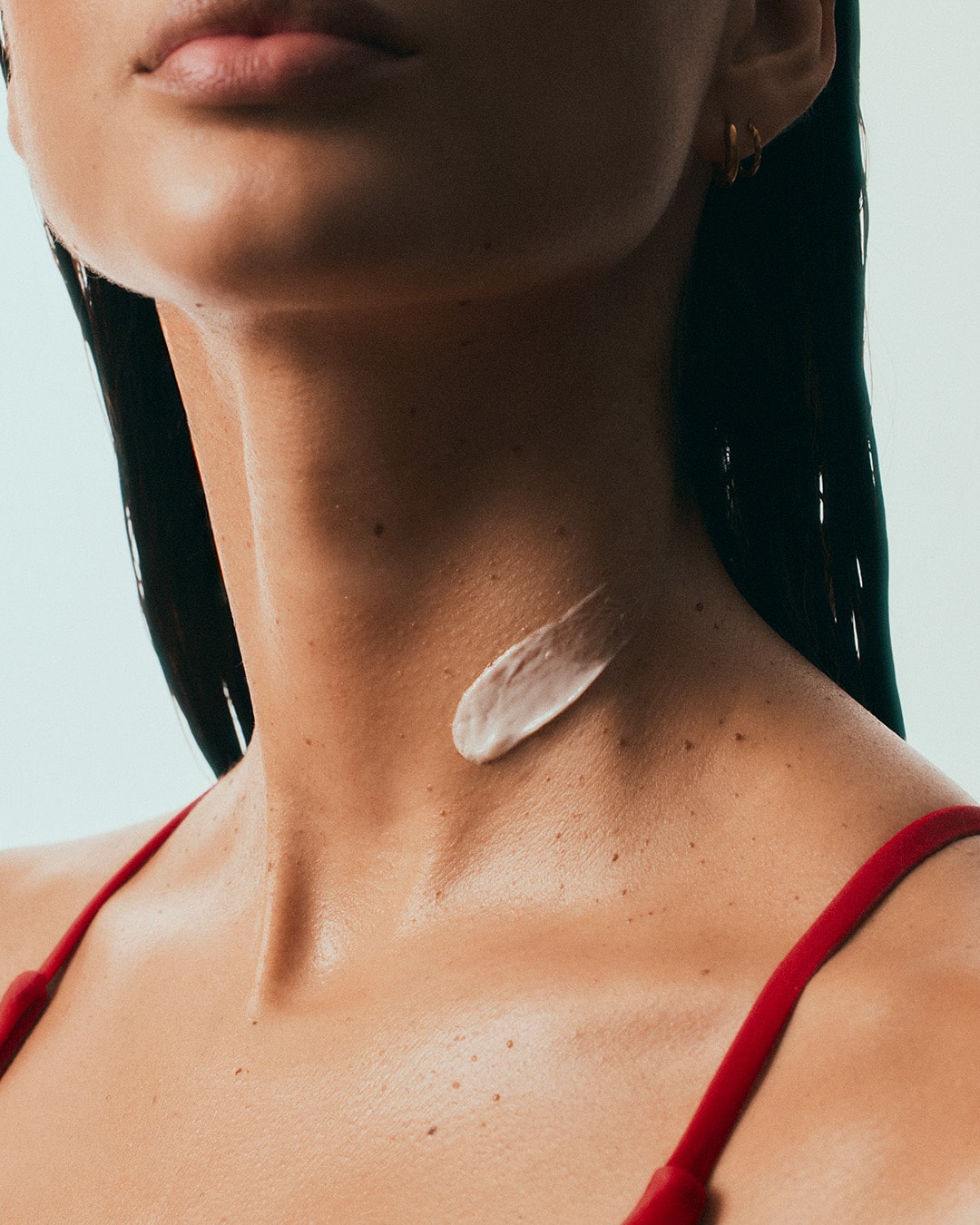 Close-up of woman applying Luisante Bakuchi neck treatment cream on her neck
