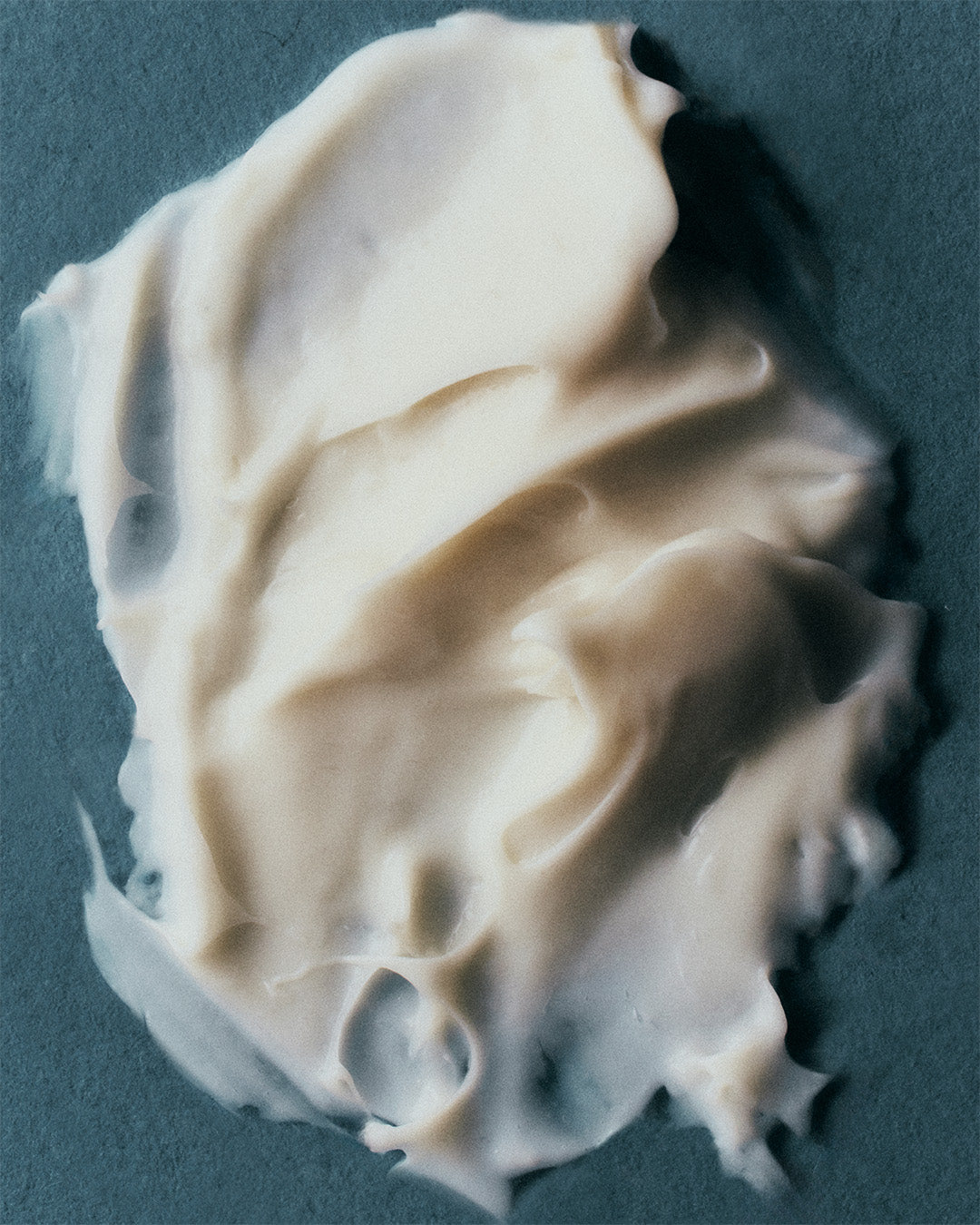 Creamy texture of Luisante Bakuchi neck treatment spread on a dark surface