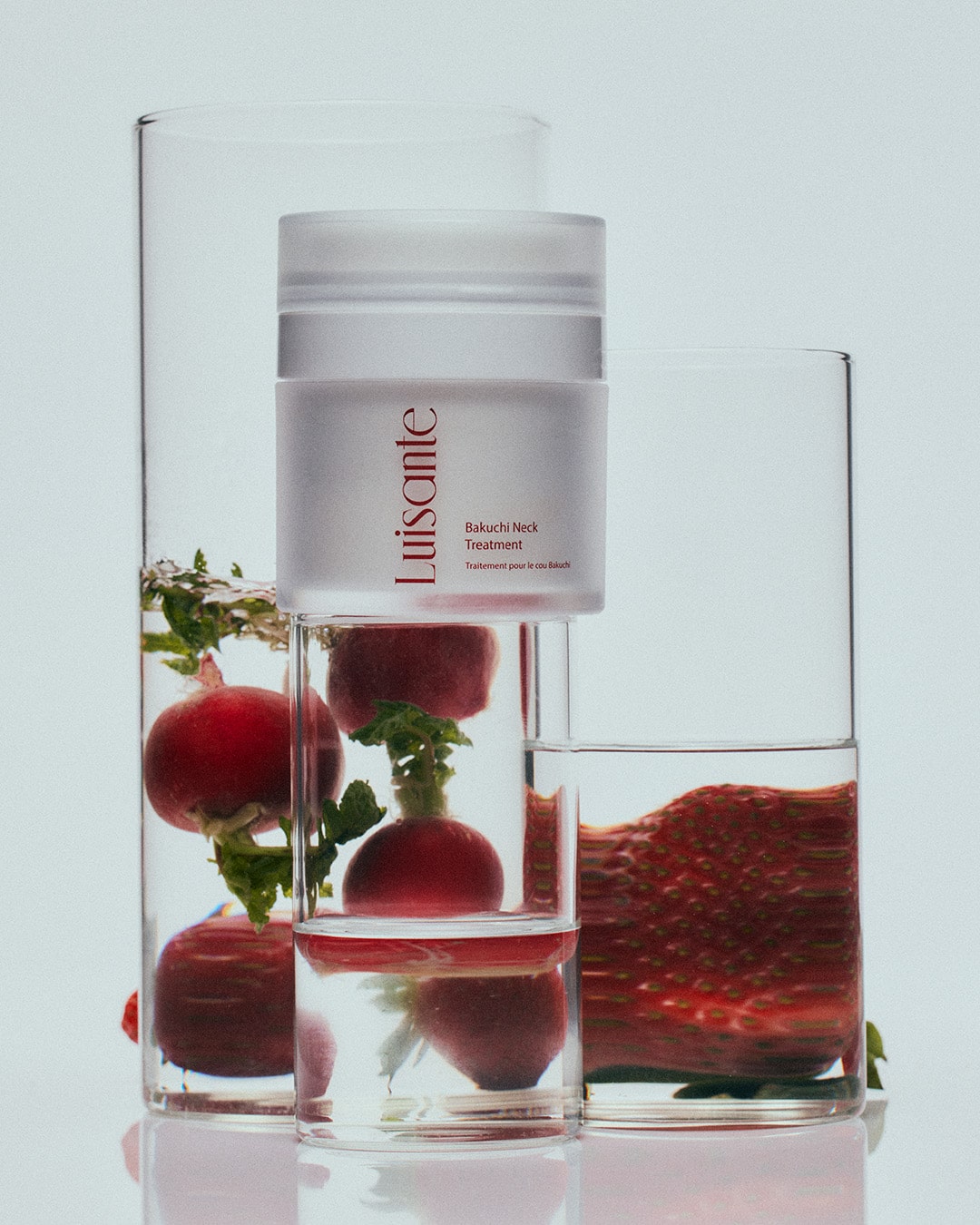 Luisante Bakuchi neck treatment cream container displayed with fresh radishes and strawberries in glass containers
