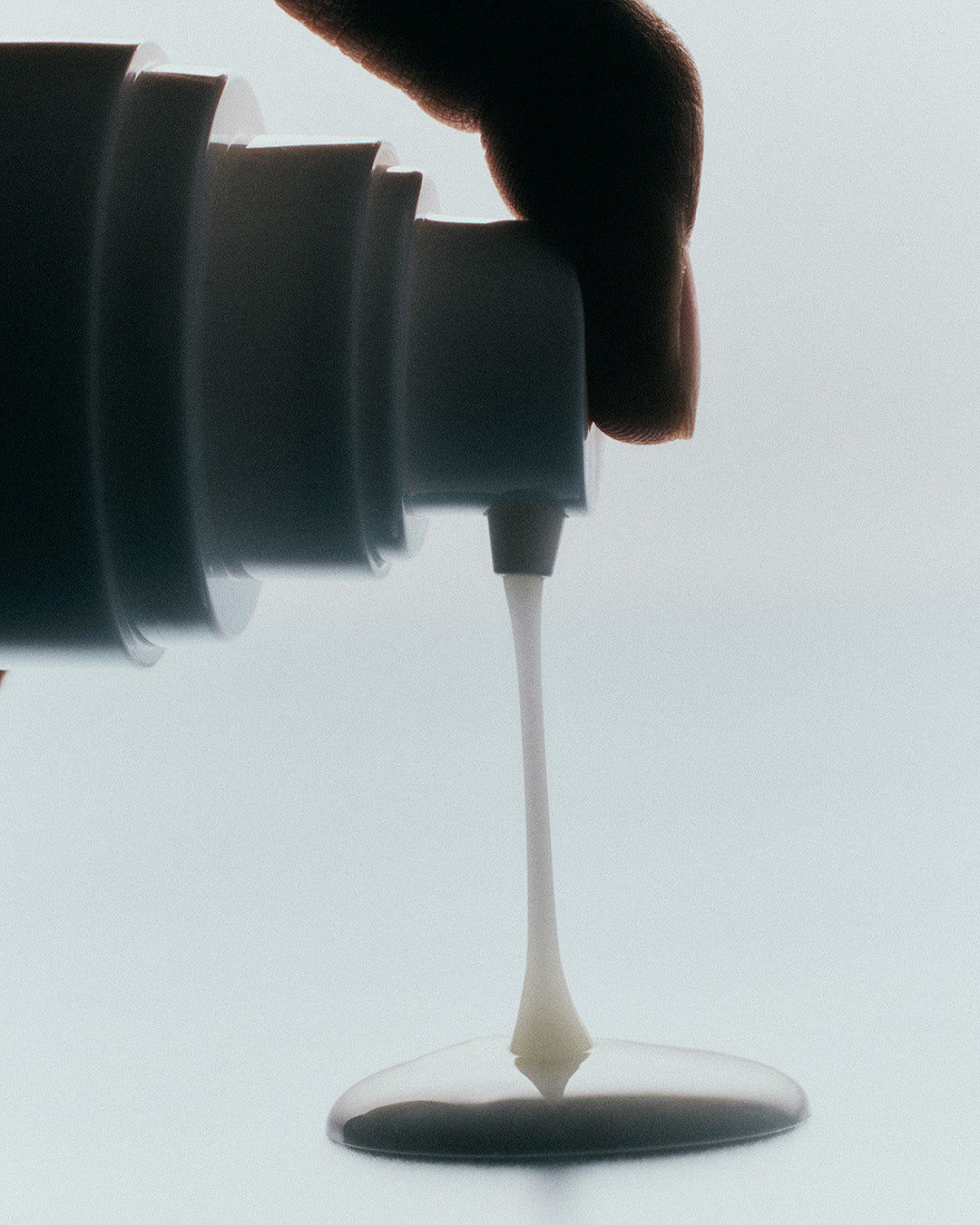 Luisante brightening body serum being dispensed from a white pump bottle showing creamy texture