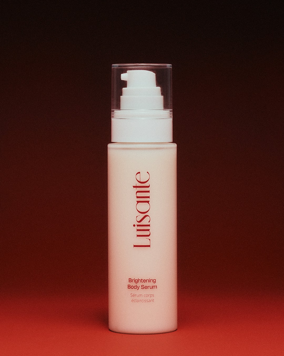 Luisante brightening body serum in a white pump bottle with red logo on a red background